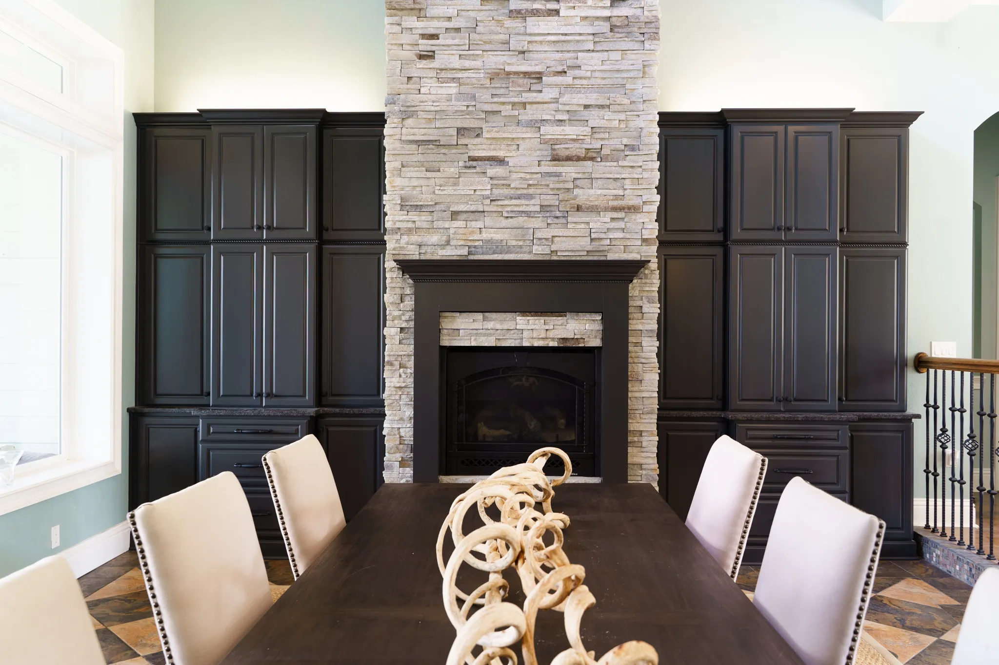 A kitchen with a dark cabinet finish either side of a stone fireplace