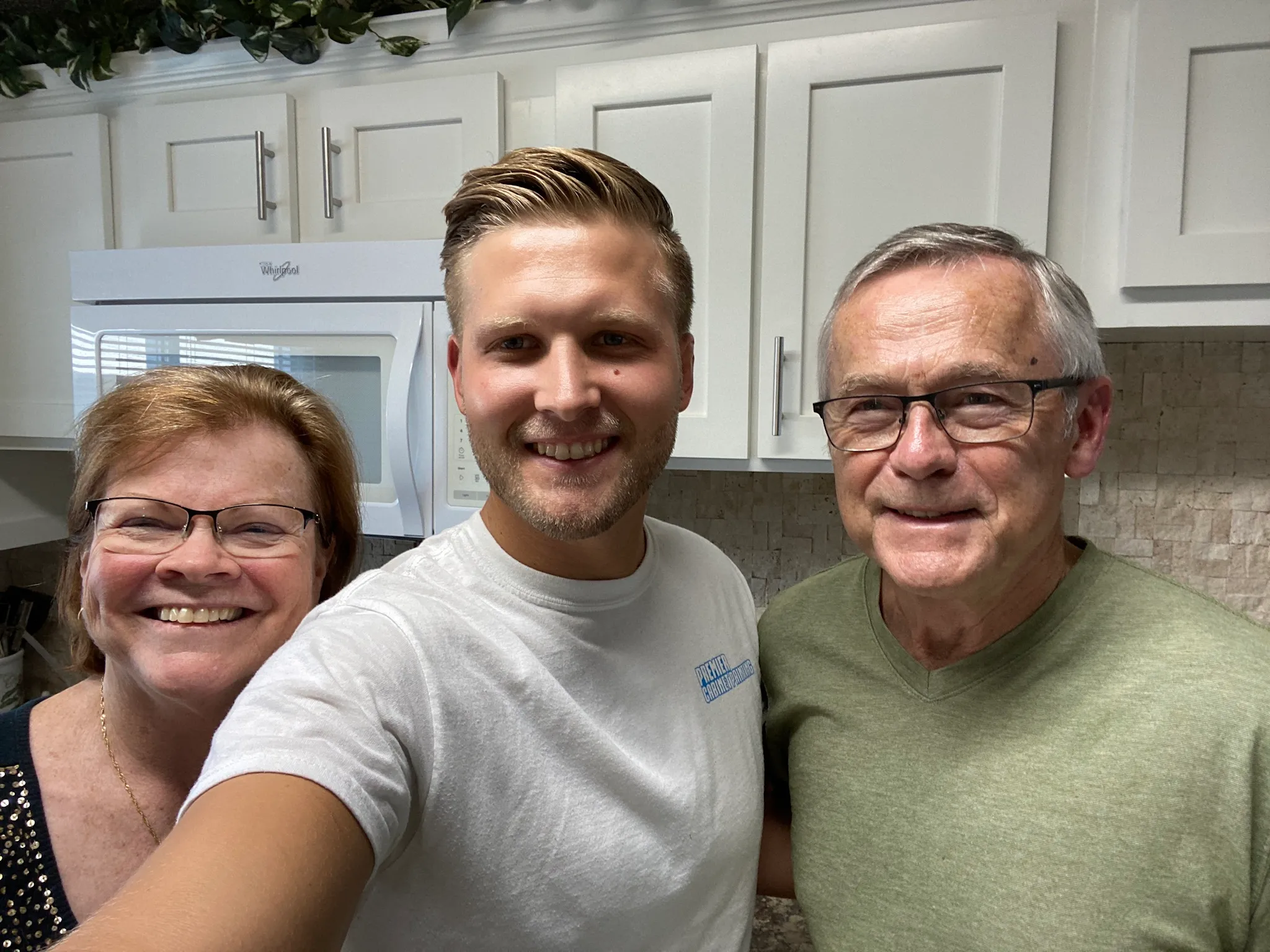 A Premier team member with the two homeowners in their finished Tampa kitchen, showing the new white MDF shaker doors and bar pull hardware