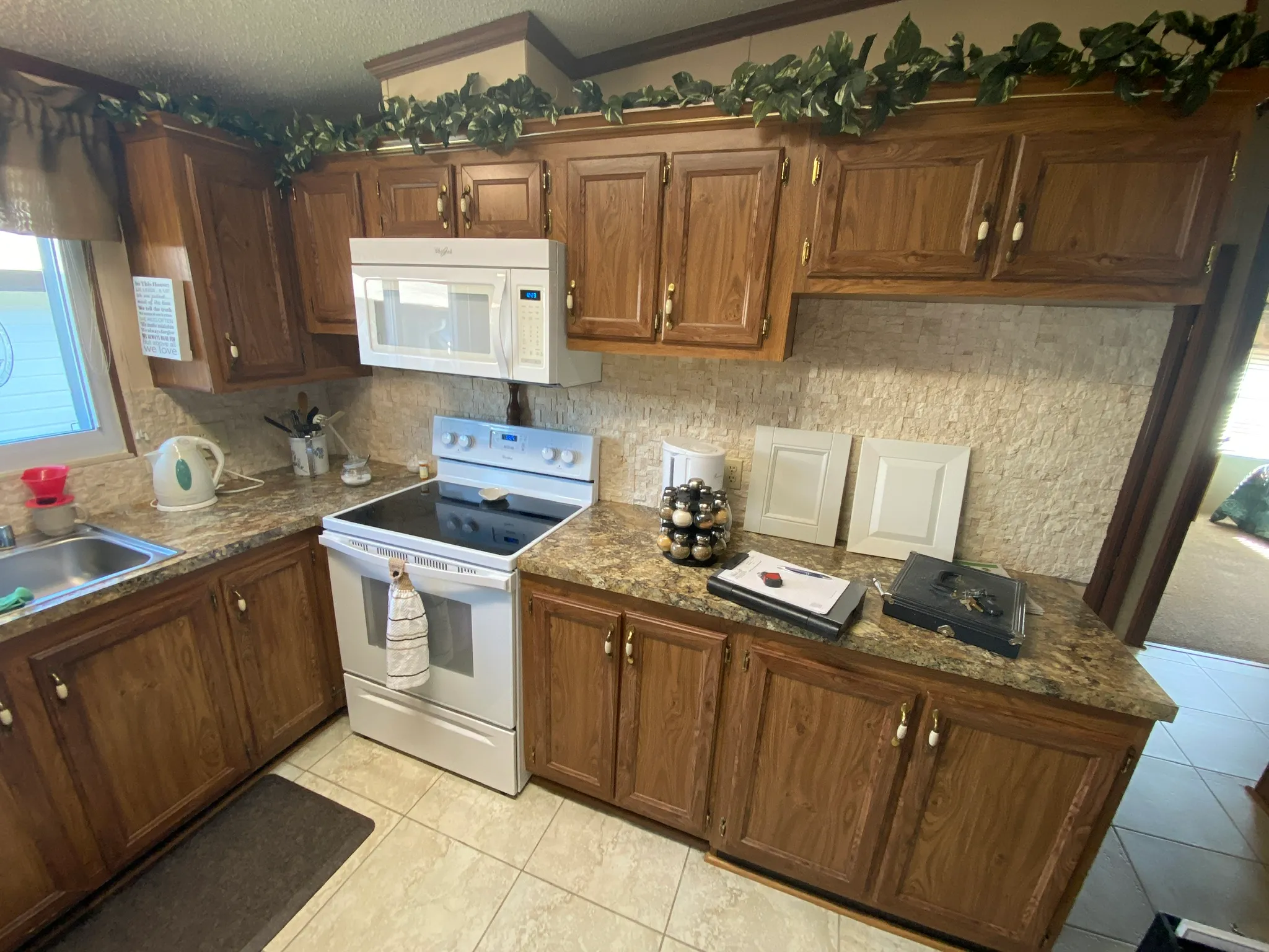 Tampa kitchen before refacing, with dark oak cathedral-arch cabinet doors, brass hardware and a white sample door propped on the counter