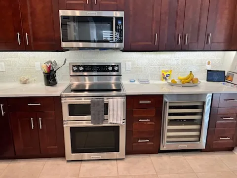 Dark cherry kitchen cabinets before painting, with wine refrigerator and range, in a Palm Harbor home