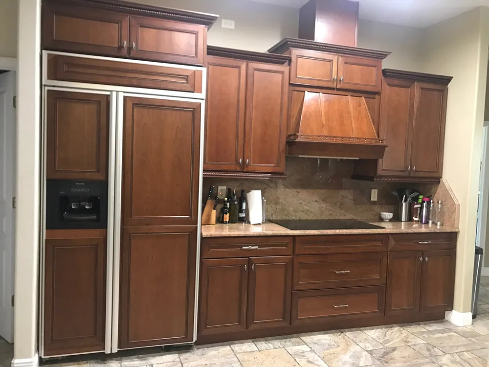 Sarasota kitchen before painting, with dark cherry cabinets, a custom wood hood and tumbled stone backsplash